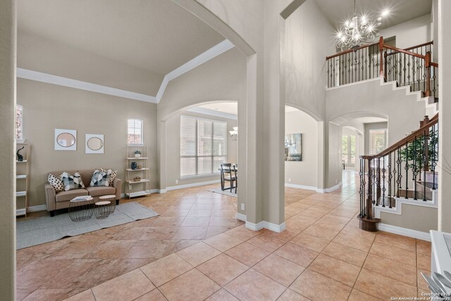 foyer with a chandelier, arched walkways, baseboards, and stairs