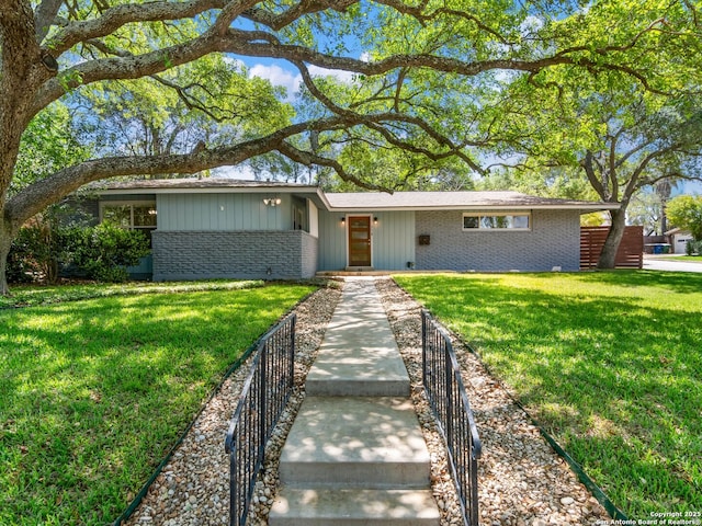 ranch-style house with a front yard, brick siding, and fence