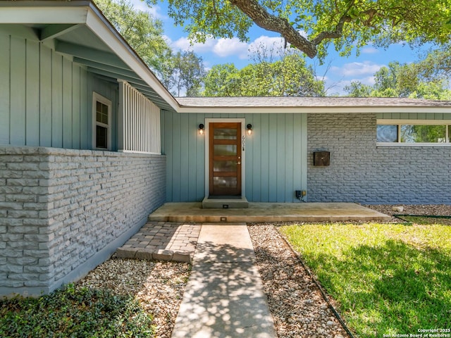 entrance to property featuring board and batten siding and brick siding