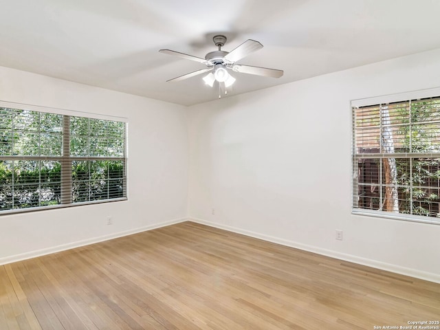 spare room featuring light wood-type flooring, a ceiling fan, and a wealth of natural light