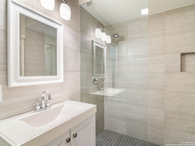 full bathroom with a tile shower, tile walls, and vanity