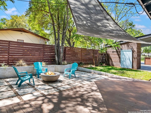 view of patio with a shed, a fenced backyard, an outdoor structure, and an outdoor fire pit