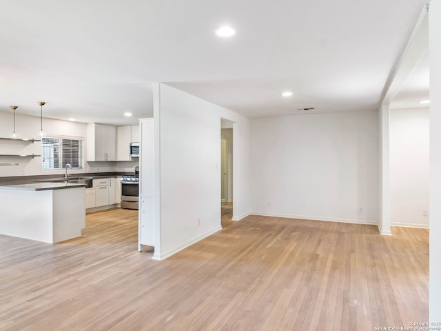 kitchen featuring light wood-type flooring, visible vents, dark countertops, stainless steel appliances, and open floor plan