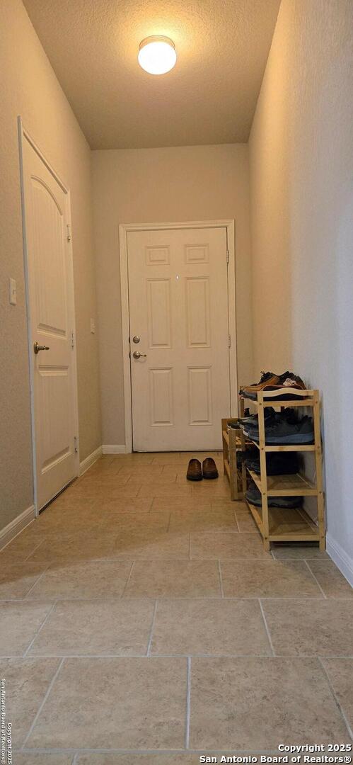 doorway to outside with baseboards and a textured ceiling