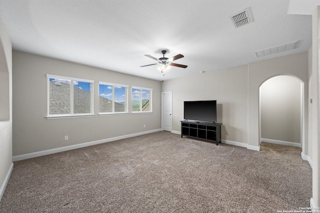 unfurnished living room with arched walkways, visible vents, a ceiling fan, and carpet floors