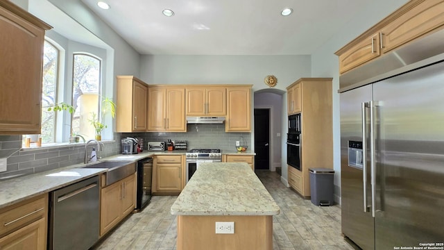 kitchen with under cabinet range hood, light brown cabinets, black appliances, and a kitchen island