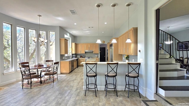 kitchen featuring visible vents, light countertops, a peninsula, under cabinet range hood, and stainless steel appliances