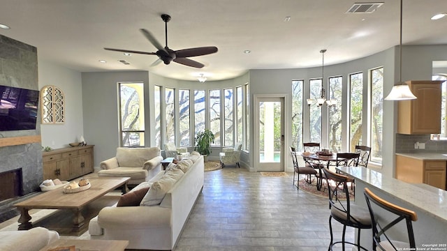 living room with a large fireplace, visible vents, recessed lighting, and ceiling fan with notable chandelier