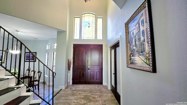 foyer entrance featuring a high ceiling, baseboards, and stairway