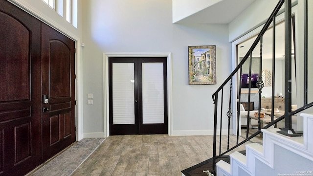 foyer entrance featuring stairs, french doors, baseboards, and wood finished floors