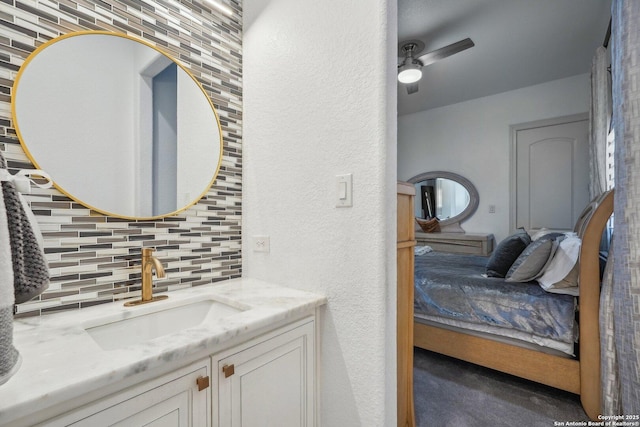 bathroom with a textured wall, vanity, a ceiling fan, and decorative backsplash