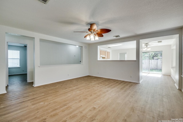 spare room featuring ceiling fan, light wood-style flooring, a textured ceiling, visible vents, and baseboards