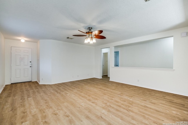 spare room featuring baseboards, a textured ceiling, a ceiling fan, visible vents, and light wood finished floors