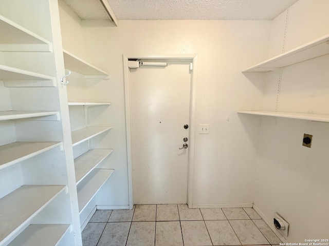 7401 Oak Marsh, Live Oak, TX 78233 - clothes washing area featuring hookup for an electric dryer, baseboards, light tile patterned floors, a textured ceiling, and laundry area