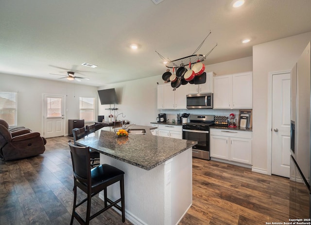 6810 Courante Waltz, San Antonio, TX 78252 - kitchen with white cabinets, open floor plan, appliances with stainless steel finishes, dark wood-style floors, and a breakfast bar area