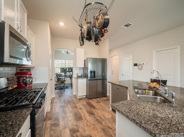 6810 Courante Waltz, San Antonio, TX 78252 - kitchen with arched walkways, a sink, wood finished floors, stainless steel appliances, and backsplash