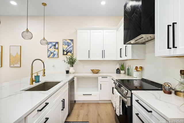 1019 S Hackberry, San Antonio, TX 78210 - kitchen featuring a sink, wall chimney range hood, light wood-type flooring, appliances with stainless steel finishes, and white cabinetry