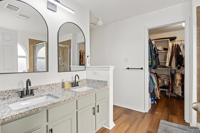 9311 Longmire, San Antonio, TX 78245 - full bathroom with wood finished floors, double vanity, a spacious closet, a stall shower, and baseboards