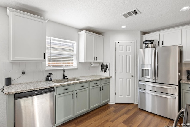 9311 Longmire, San Antonio, TX 78245 - kitchen with stainless steel appliances, a sink, dark wood-style flooring, decorative backsplash, and white cabinets