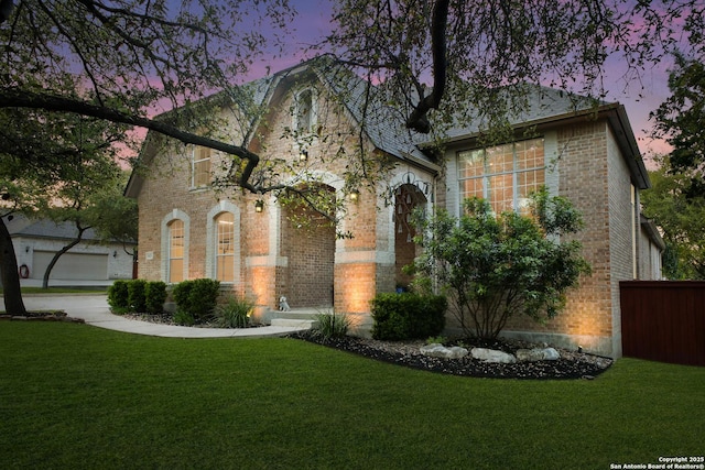 view of front of house with fence, a yard, and brick siding