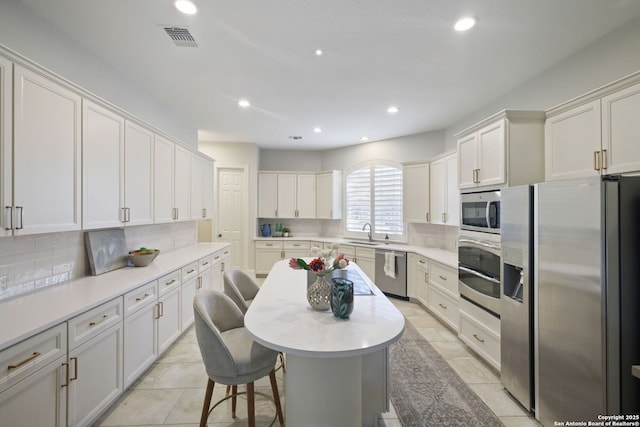 kitchen with appliances with stainless steel finishes, decorative backsplash, a sink, and visible vents
