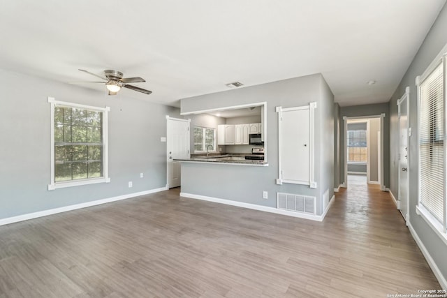 2415 Spicewood, San Antonio, TX 78213 - unfurnished living room featuring ceiling fan, light wood-style flooring, baseboards, and a sink