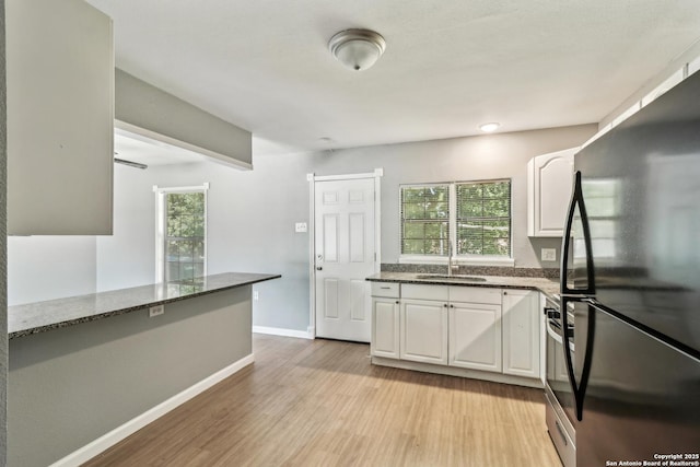 2415 Spicewood, San Antonio, TX 78213 - kitchen with freestanding refrigerator, a sink, white cabinetry, light wood finished floors, and dark stone countertops