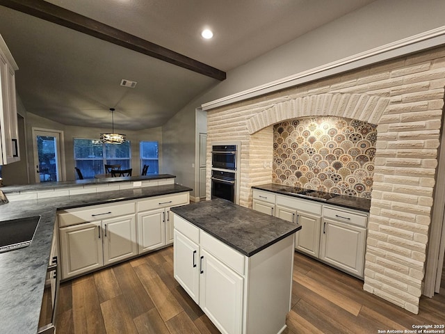 kitchen with dark countertops, double oven, a peninsula, and dark wood-style floors