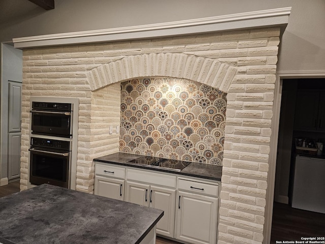 kitchen featuring washer / dryer, white cabinets, dark countertops, and black electric cooktop