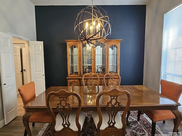 dining space featuring a towering ceiling, a chandelier, and wood finished floors