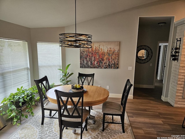 dining space with a chandelier, lofted ceiling, baseboards, and wood finished floors