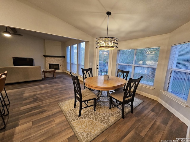 dining room with a fireplace, a notable chandelier, dark wood finished floors, and vaulted ceiling