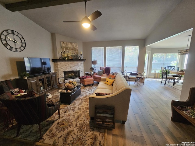 living area featuring a fireplace, vaulted ceiling with beams, a ceiling fan, and wood finished floors