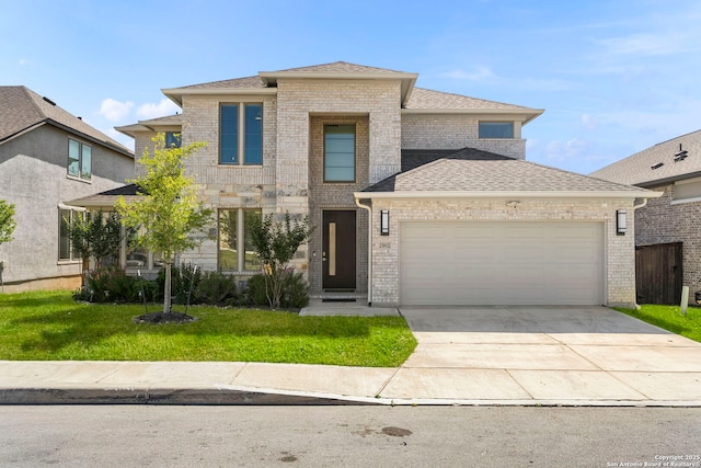 view of front of home with a shingled roof, concrete driveway, an attached garage, brick siding, and a front yard