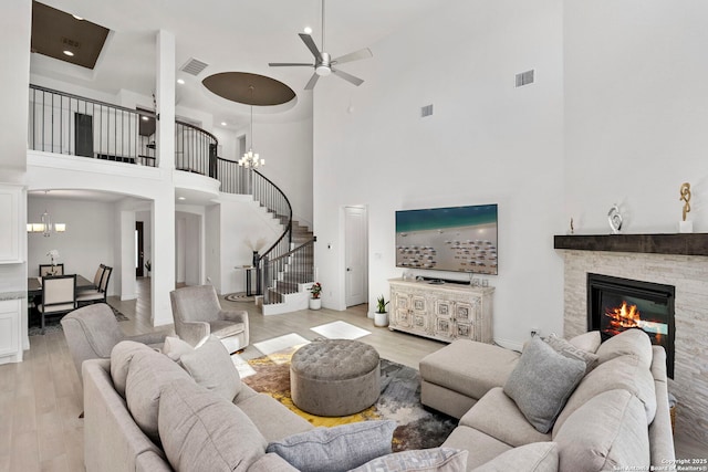 living room with visible vents, a high ceiling, light wood finished floors, and stairway