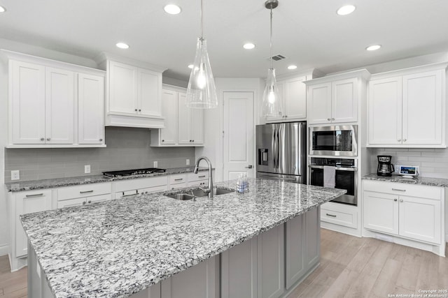 kitchen with custom exhaust hood, a sink, stainless steel appliances, backsplash, and visible vents