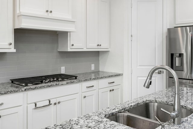 kitchen featuring a sink, decorative backsplash, appliances with stainless steel finishes, custom exhaust hood, and white cabinetry