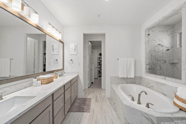 bathroom with a spacious closet, a garden tub, a sink, and double vanity