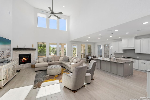 living room with a fireplace, light wood finished floors, and a ceiling fan