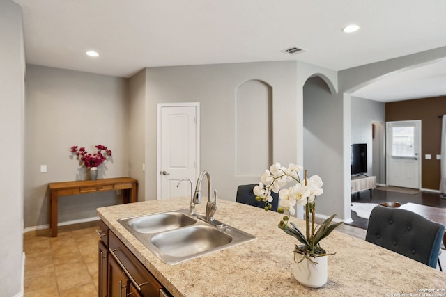 kitchen with baseboards, recessed lighting, visible vents, arched walkways, and a sink