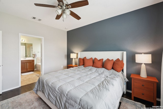 bedroom featuring ensuite bathroom, a ceiling fan, visible vents, wood finished floors, and baseboards