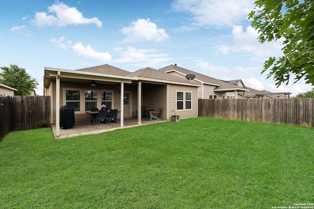 back of house featuring a yard, roof with shingles, a fenced backyard, and a patio area