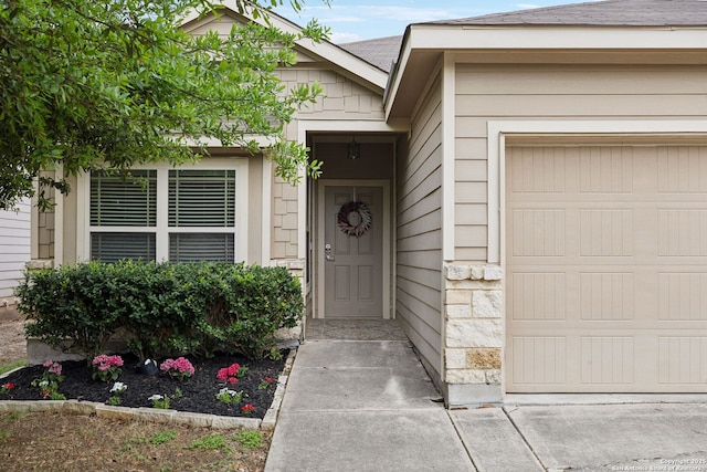 view of exterior entry featuring an attached garage and stone siding