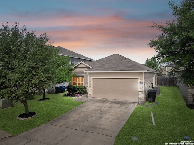 view of front of home featuring a garage, a yard, central air condition unit, and driveway