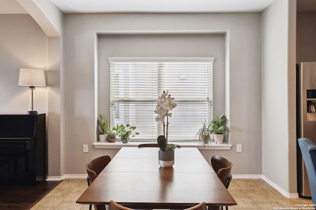 dining area featuring arched walkways, baseboards, and tile patterned flooring