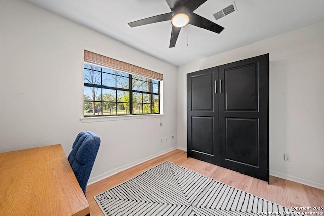 office space featuring light wood-style floors, visible vents, baseboards, and a ceiling fan