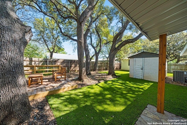 view of yard featuring cooling unit, an outbuilding, a fenced backyard, and a storage unit