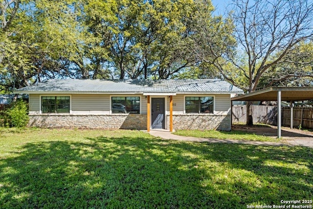 view of front of house featuring stone siding, a detached carport, fence, and a front lawn