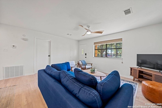 living area featuring light wood-type flooring, ceiling fan, baseboards, and visible vents