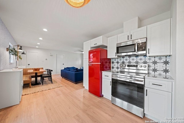 kitchen featuring light wood-style flooring, light countertops, white cabinetry, backsplash, and appliances with stainless steel finishes